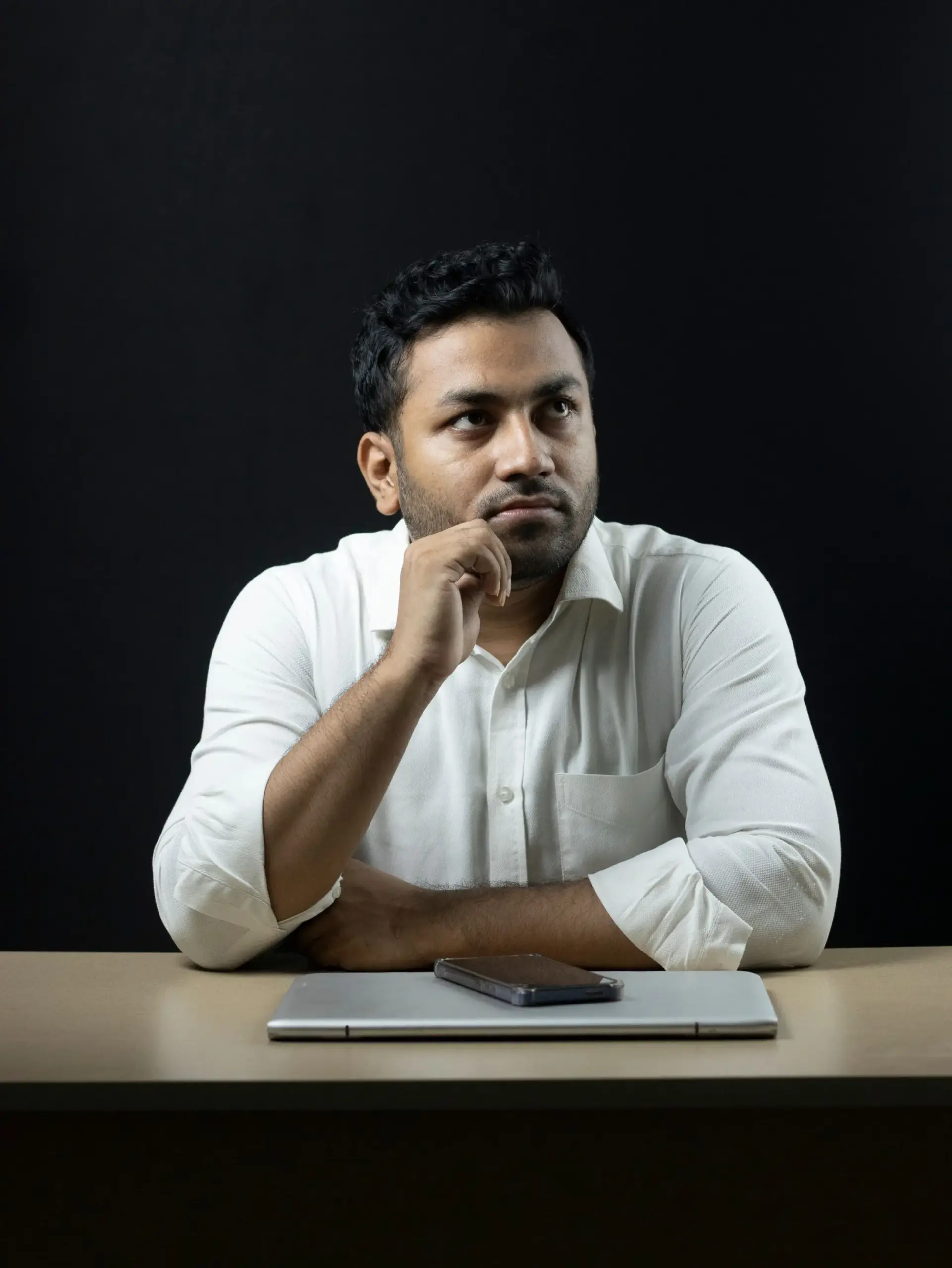 Indian businessman seated at an office desk with laptop and phone